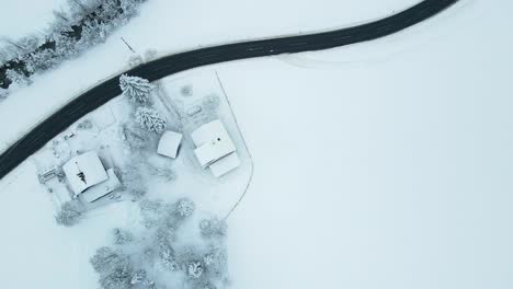 Toma-Aérea-De-Un-Pueblo-De-Montaña-Cubierto-De-Nieve,-Camino-Sinuoso-A-Través-Del-Valle