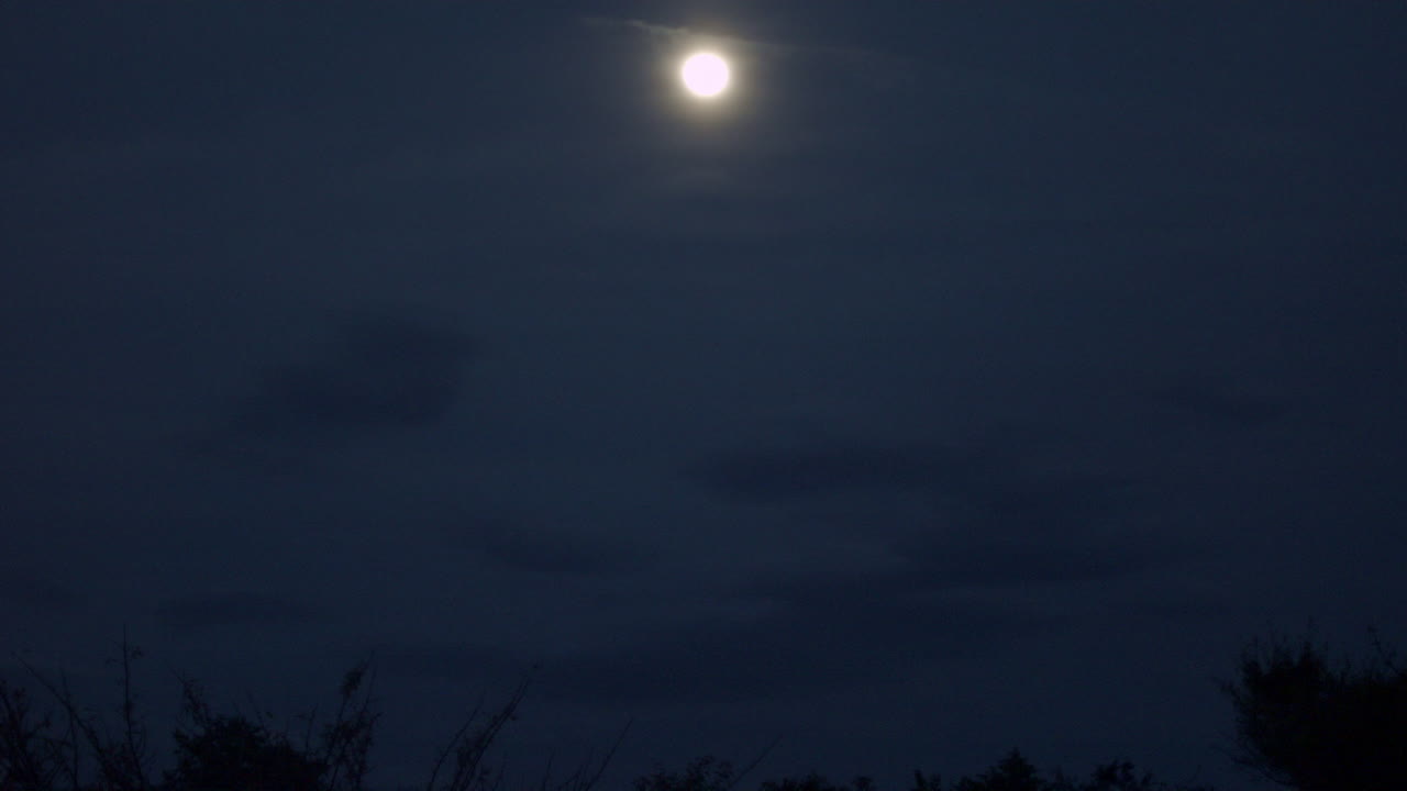 Nuvole nere che passano davanti a una luna piena nel cielo notturno