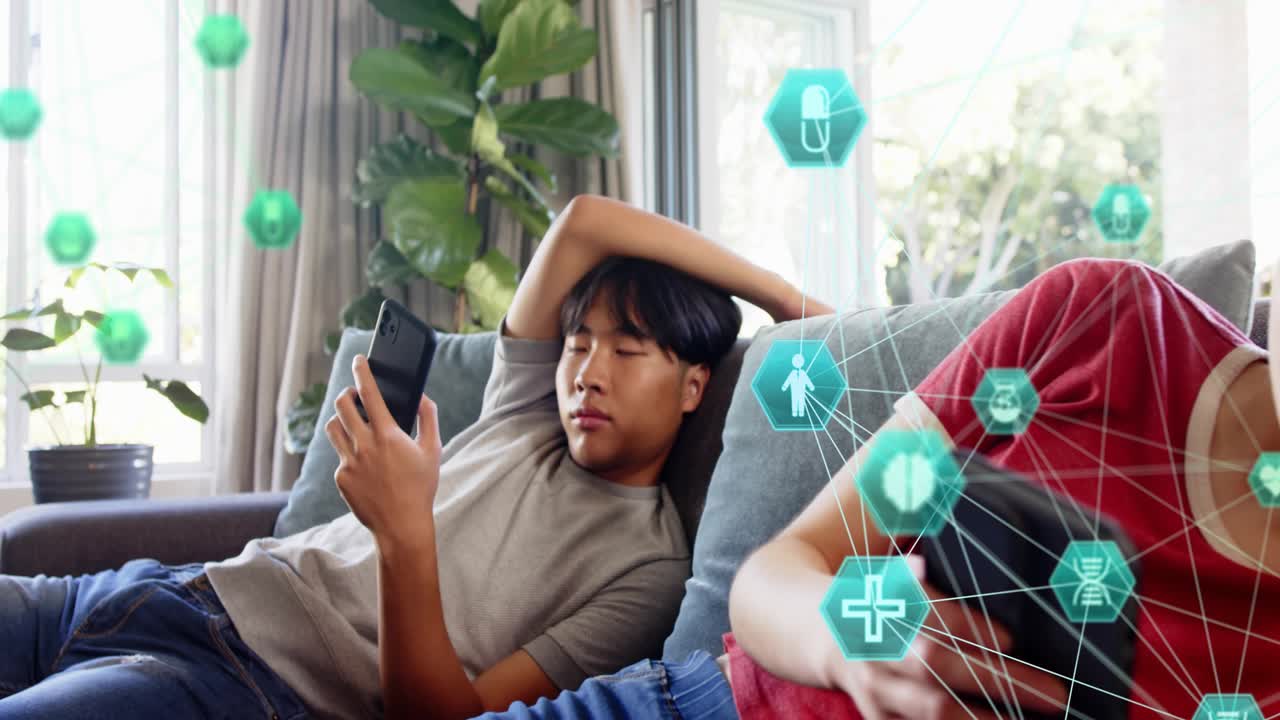 Man reclining, woman scrolling on couch, tapping phones and activating teal health icons around her