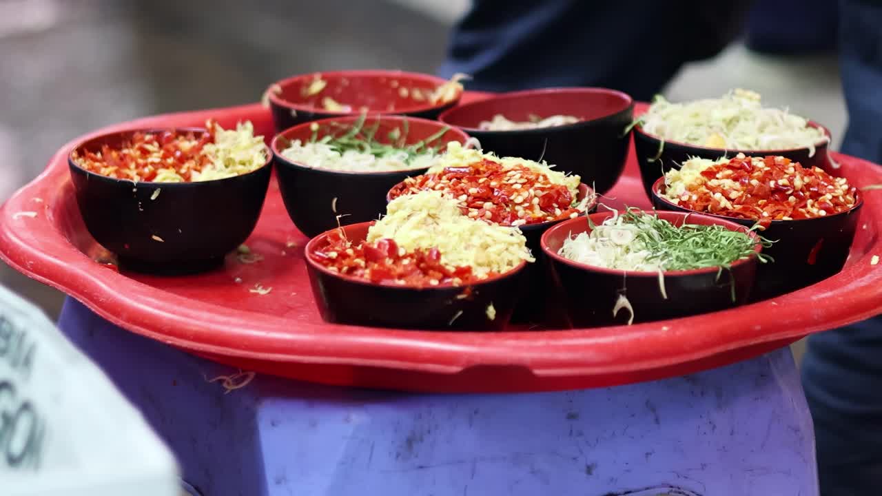A vibrant assortment of food bowls arranged on a red tray, showcasing a variety of colorful ingredients.