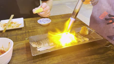 chef uses blowtorch to sear fish dish