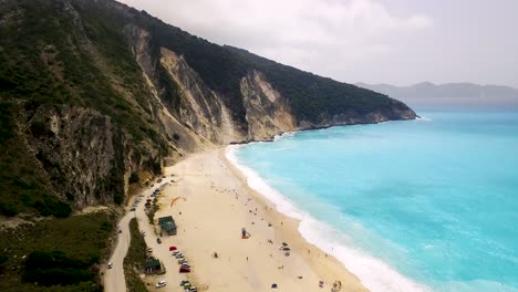 Playa-De-Myrtos-En-La-Isla-De-Cefalonia,-Con-Aguas-Turquesas-Y-Arenas-Blancas,-Con-Un-Telón-De-Fondo-Montañoso,-Vista-Aérea