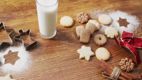 video of christmas decorations with an assortment of cookies and glass of milk on wooden background