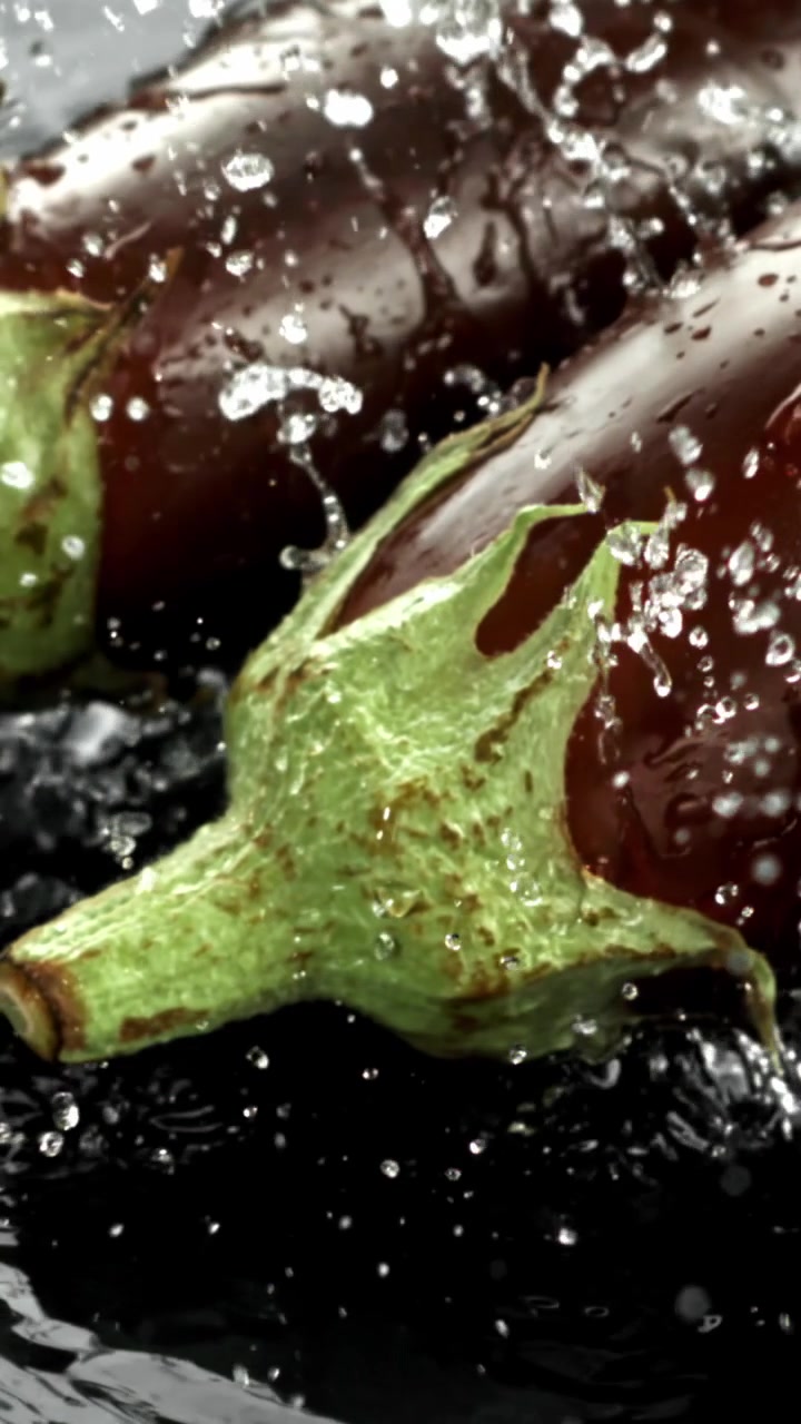 Primo piano di melanzane fresche che schizzano nell'acqua
