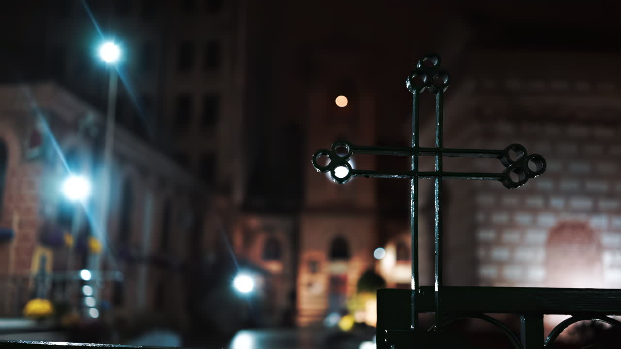 A metal green cross at night with buildings on the background in Bucharest, Romania