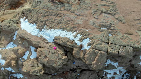 elevando la vista de drones de los escaladores subiendo a la cima de una montaña rocosa en colorado durante el invierno