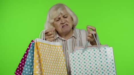 abuela sosteniendo bolsas de compras, regocijándose de los descuentos en la tienda, disfrutando de las compras con precios bajos