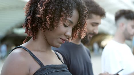 uma mulher afro-americana alegre a enviar mensagens de texto com um smartphone.