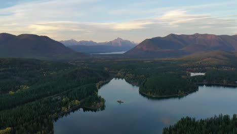 beautiful sunset view of lush forest and idyllic mountain range surrounding lake five resort in montana - aerial shot