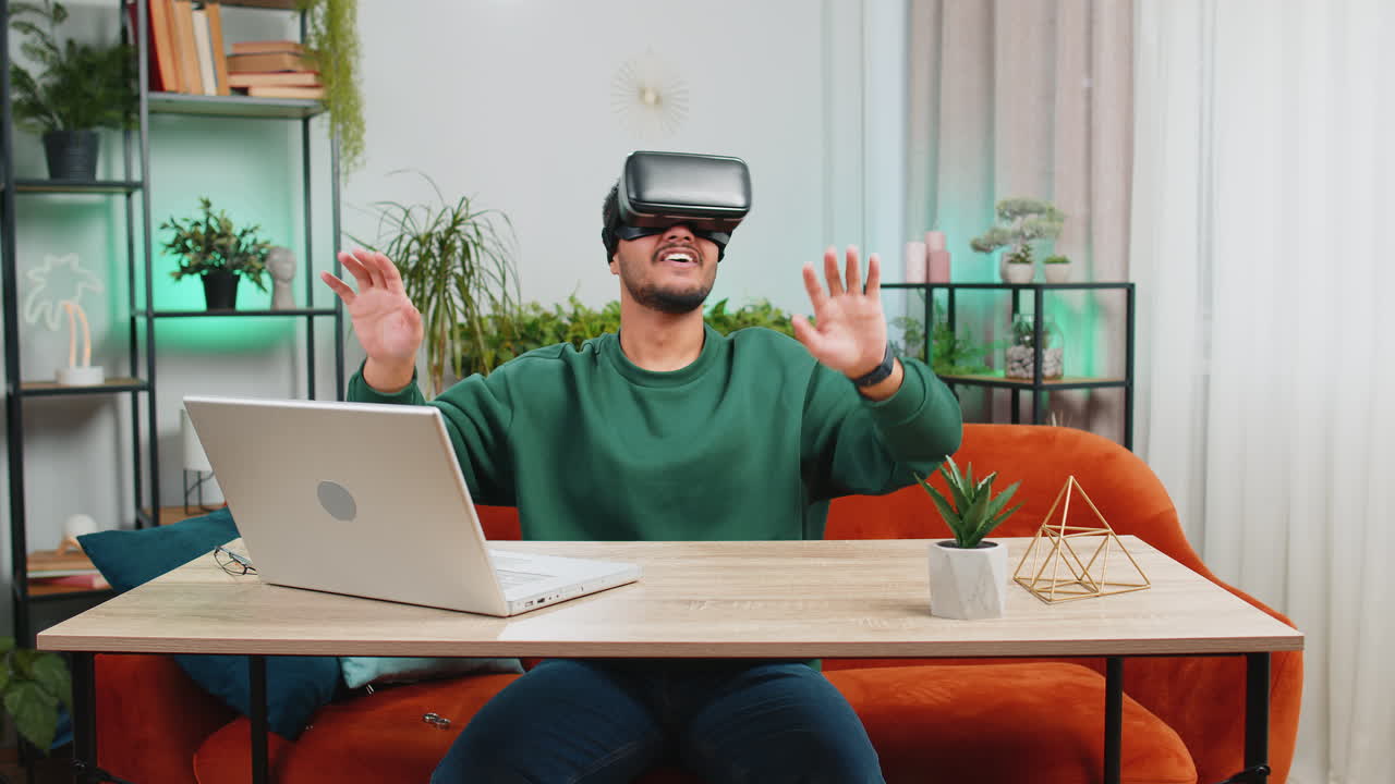 Indian man using virtual reality futuristic technology headset play simulation 3d video game at home