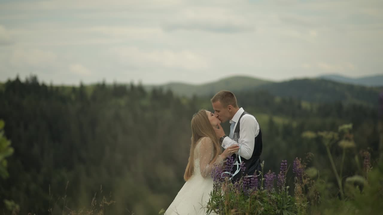 Gom og brud drikker champagne på bjergskråninger. Brudepar. Familie.