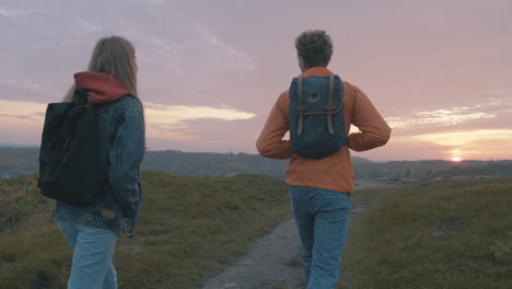 prachtige zonsondergang jong stel vrouwelijke en mannelijke wandelaars op de top van de berg