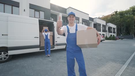 two young workers of removal company are loading boxes and furniture into a minibus