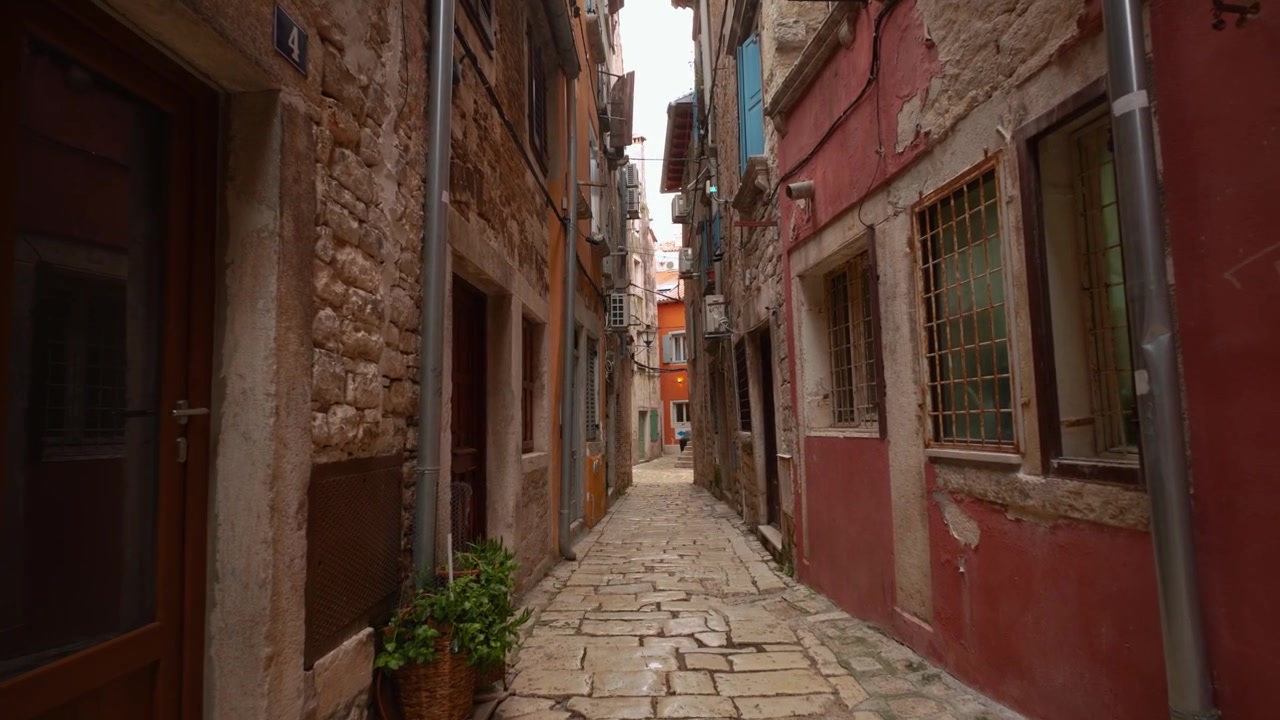 Stretto vicolo acciottolato con edifici rustici e antichi nel centro storico di Rovigno. Movimento in avanti.