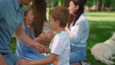 padre de mediana edad cosquilleando a su hijo en un picnic en primer plano. familia activa jugando juegos divertidos