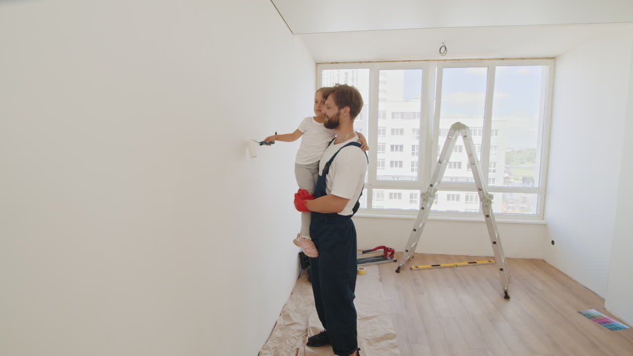 ojciec i córka malują razem ścianę.