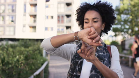 beautiful mixed race woman using smart watch technology walking through city