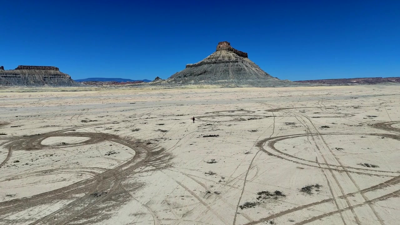 Donna che cammina al rallentatore verso Factory Butte nel deserto dello Utah.