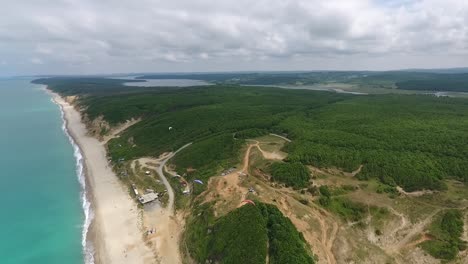 parapentes volando sobre colinas verdes y drones junto al mar