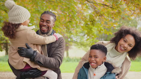 portrait of smiling family with parents with children on walk through autumn countryside together looking at camera - shot in slow motion