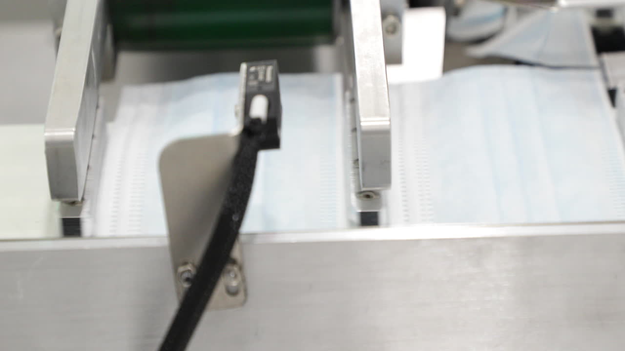 mascarilla quirúrgica de 3 capas que sale de la máquina para sujetar el bucle de la oreja