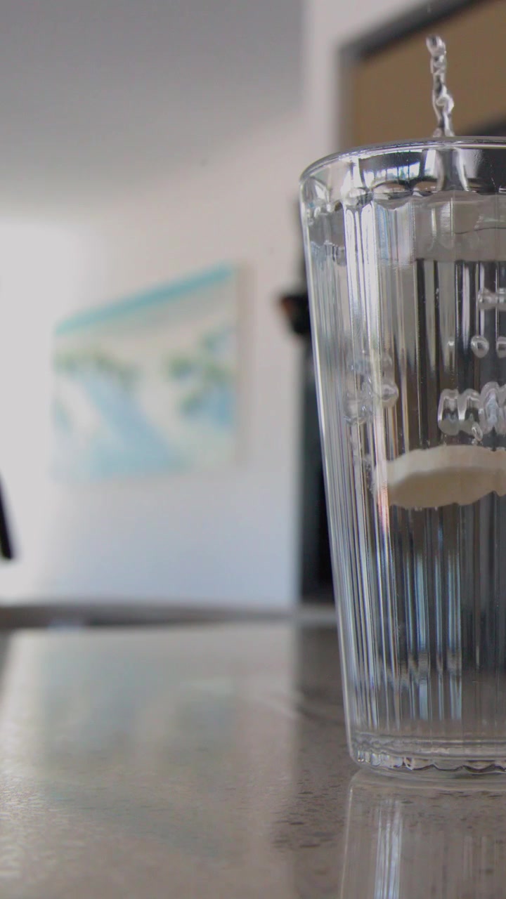 Primo piano di una compressa effervescente bianca che si dissolve con bollicine in un bicchiere trasparente.