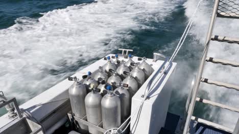 scuba diving tanks and equipment secured on a dive boat travelling to the great barrier reef