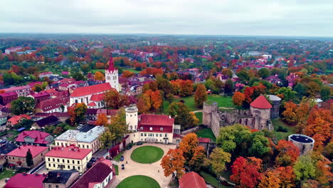 aerial backward moving shot over iconic medieval castle called cēsis castle in latvia at daytime with the view of a town in the background on a cloudy day