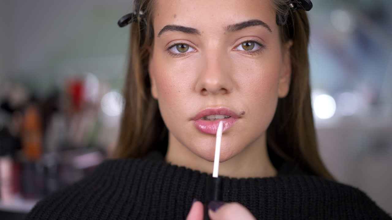 Woman Applying Lip Gloss During a Beauty Session