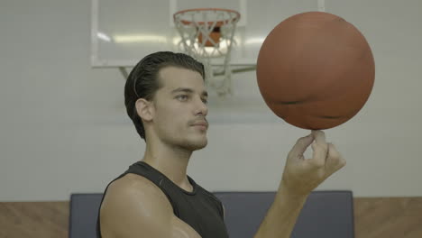 close up profile, young man spinning ball on finger, basketball court