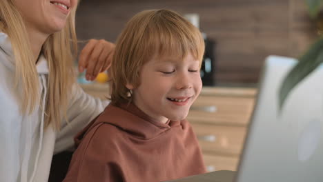 little boy and mother having fun with laptop at home