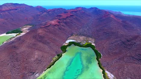 reverse flying drone to reveal striking desert mountain valley leading towards unique underwater algae and sand formations