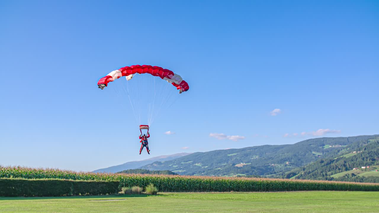 two skydivers smooth tandem landing on green grass field. Adrenaline rush jump