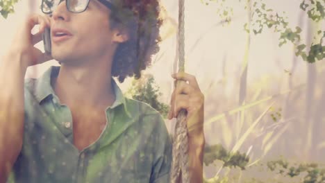 Man-sitting-on-a-swing-while-calling-on-his-phone