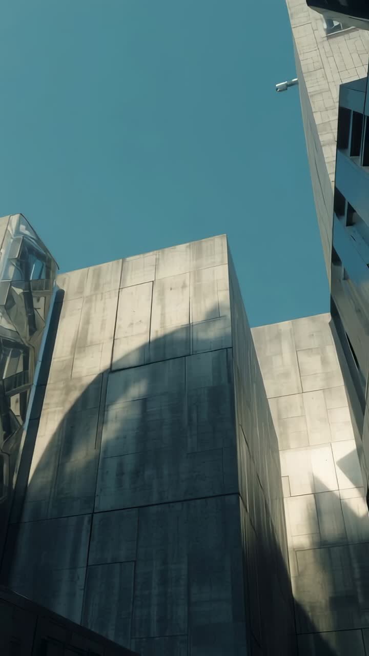 Vídeo vertical: luz solar en movimiento proyectando sombras sobre la fachada de hormigón en el patio, marcando el tiempo