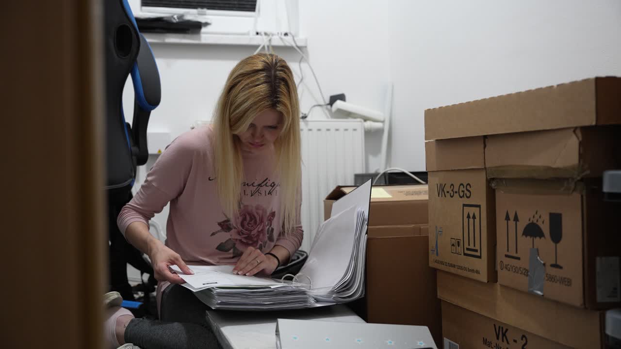A young lady checks documents in a room full of cardboard boxes ready for the move