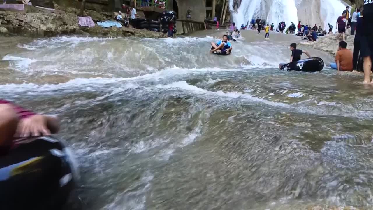 Peoples sliding use tires in front of the Bantimurung waterfall in Maros, South Sulawesi. Karst stone site.