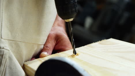 Focus-on-a-drill-drilling-a-whole-in-a-wood-plank