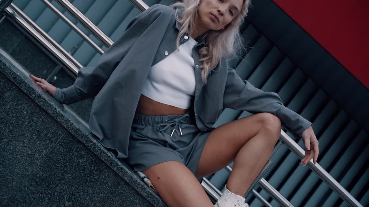 Woman modeling street style with blonde hair in urban background.