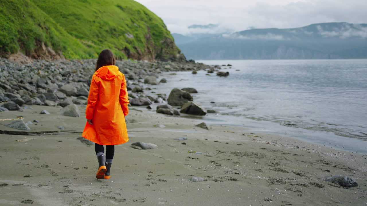 Woman in raincoat walking on a beach