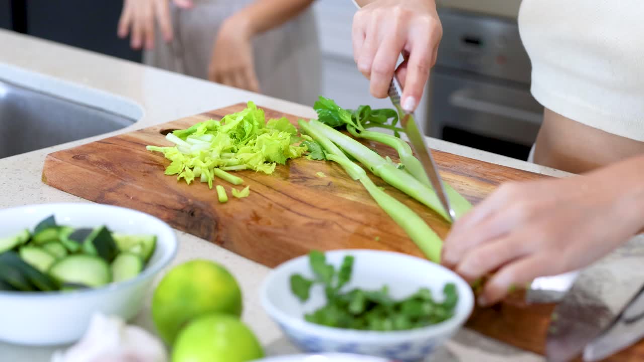 Hands slicing celery on a wooden board in a bright kitchen. Fresh ingredients and natural lighting create a vibrant atmosphere