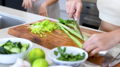 hands slicing celery on a wooden board in a bright kitchen. fresh ingredients and natural lighting create a vibrant atmosphere