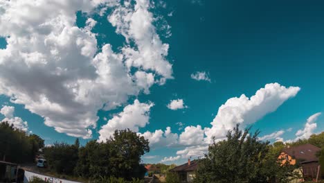 Zeitraffer-Von-Wolken,-Die-über-Einen-Türkisfarbenen-Himmel-über-Einem-Vorort-Mit-Häusern-Und-Bäumen-Laufen