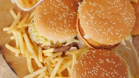 porción de comida no saludable, comida rápida, pila de hamburguesas, patatas fritas girando, vista desde arriba