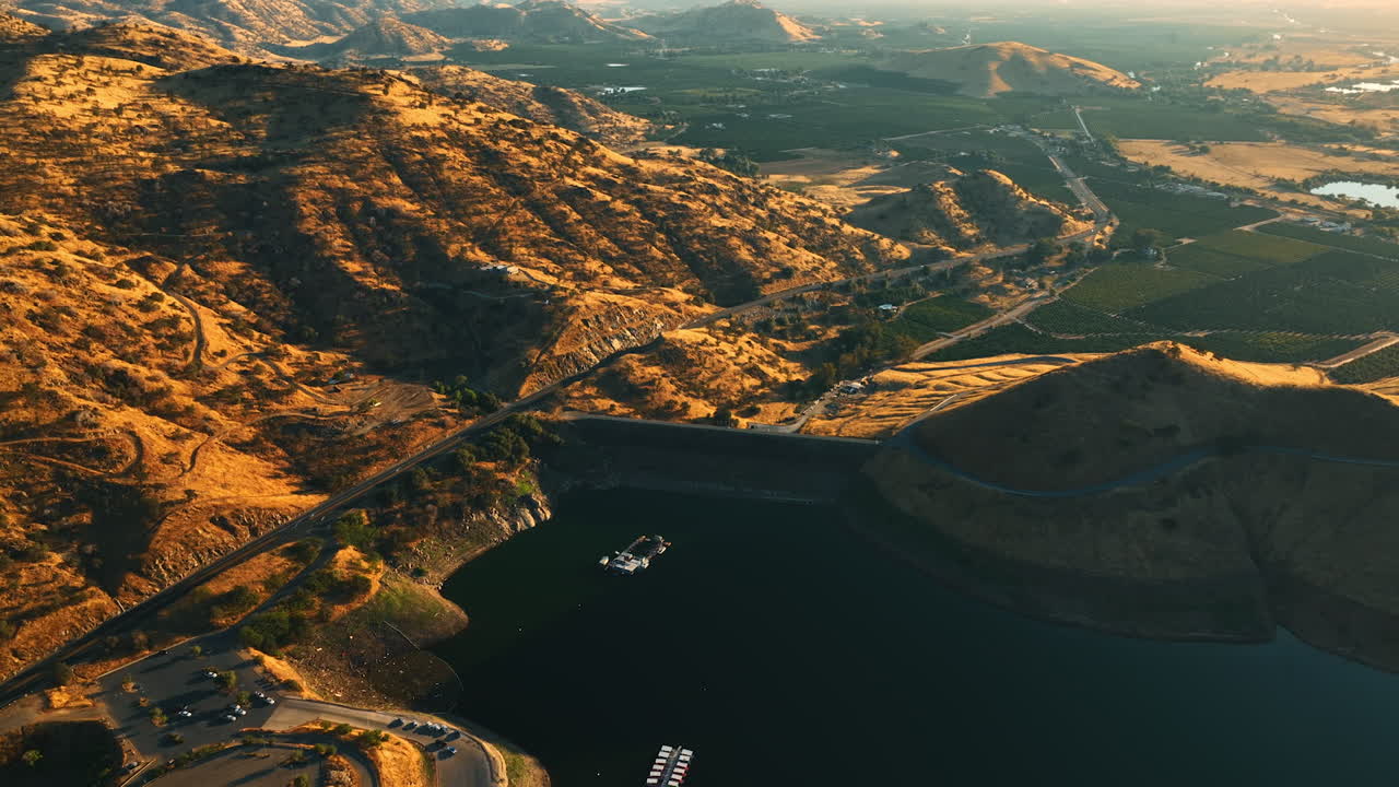 Flying above the lake in the mountains of California. Sunny green valleys at backdrop. View from aerial perspective.