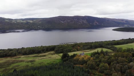 Aerial-View-Over-Green-Valley-River-Bank-Trees-With-Loch-Ness-In-The-Scottish-Highlands