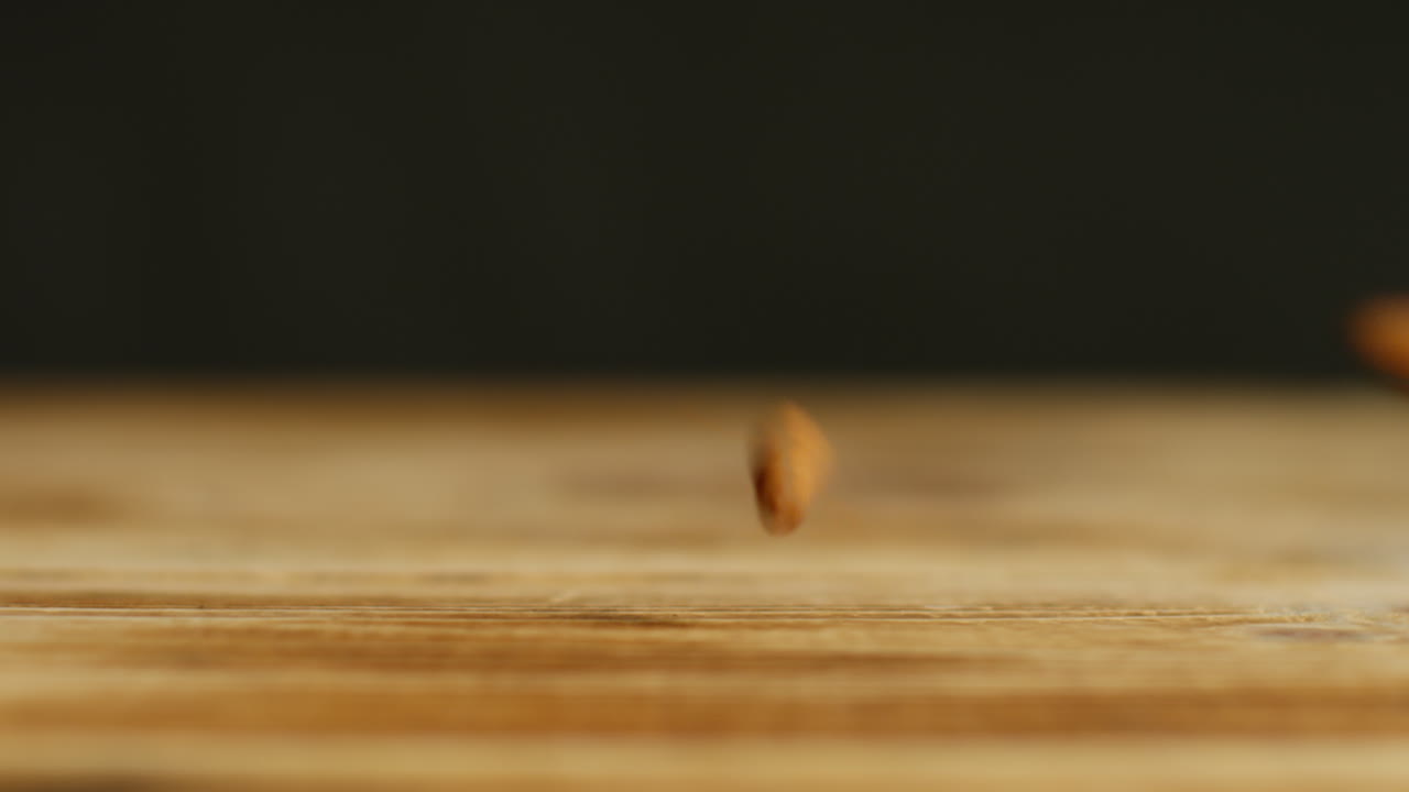 fotografía de cerca de nueces de almendra cayendo sobre una superficie de madera contra un fondo de estudio negro tomada en cámara lenta
