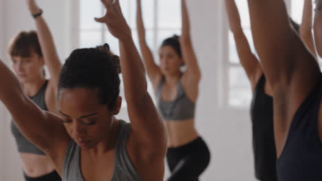 Hermosa-Mujer-De-Yoga-De-Raza-Mixta-Practicando-Meditación-En-Pose-Guerrera-Con-Un-Grupo-De-Mujeres-Multirraciales-Disfrutando-De-Un-Estilo-De-Vida-Saludable-Haciendo-Ejercicio-En-El-Gimnasio