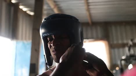 allenatore che indossa il casco al pugile in palestra