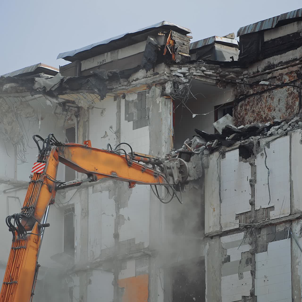 Hydraulic crasher of an excavator machine demolishing the house. High building wrecked by an earthquake being destroyed by a special machinery. Dust spreads all over the place